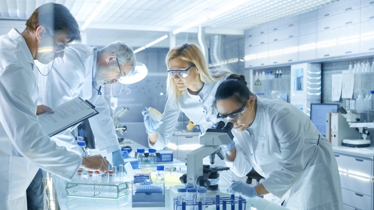 Team of Medical Research Scientists Work on a New Generation Disease Cure. They use Microscope, Test Tubes, Micropipette and Writing Down Analysis Results. Laboratory Looks Busy, Bright and Modern.